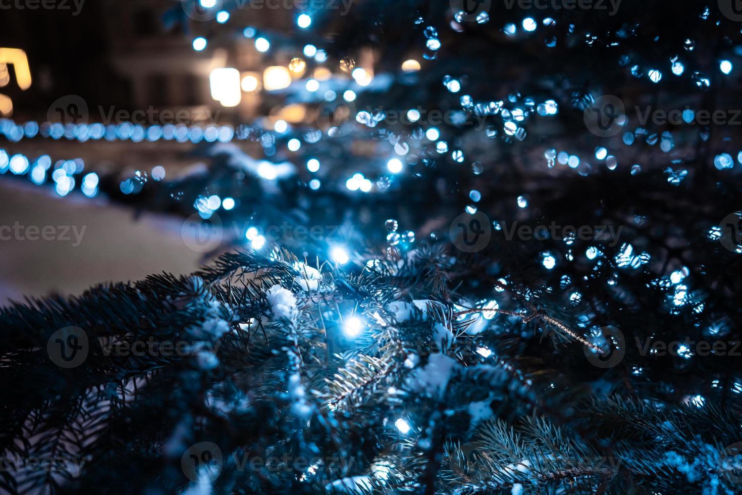 Christmas tree with cones on a city street illuminated with a garland. photo