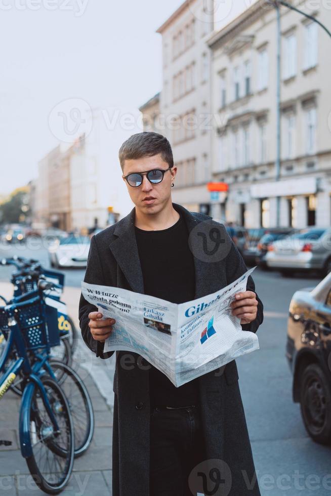 Smart man in sunglasses with paper on street photo