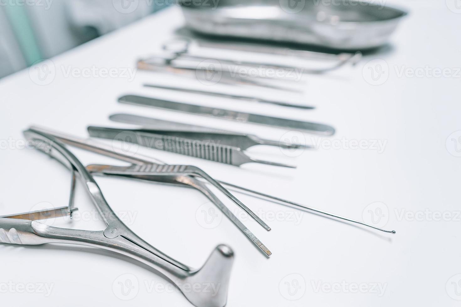 Several surgical instruments lie on a white table photo