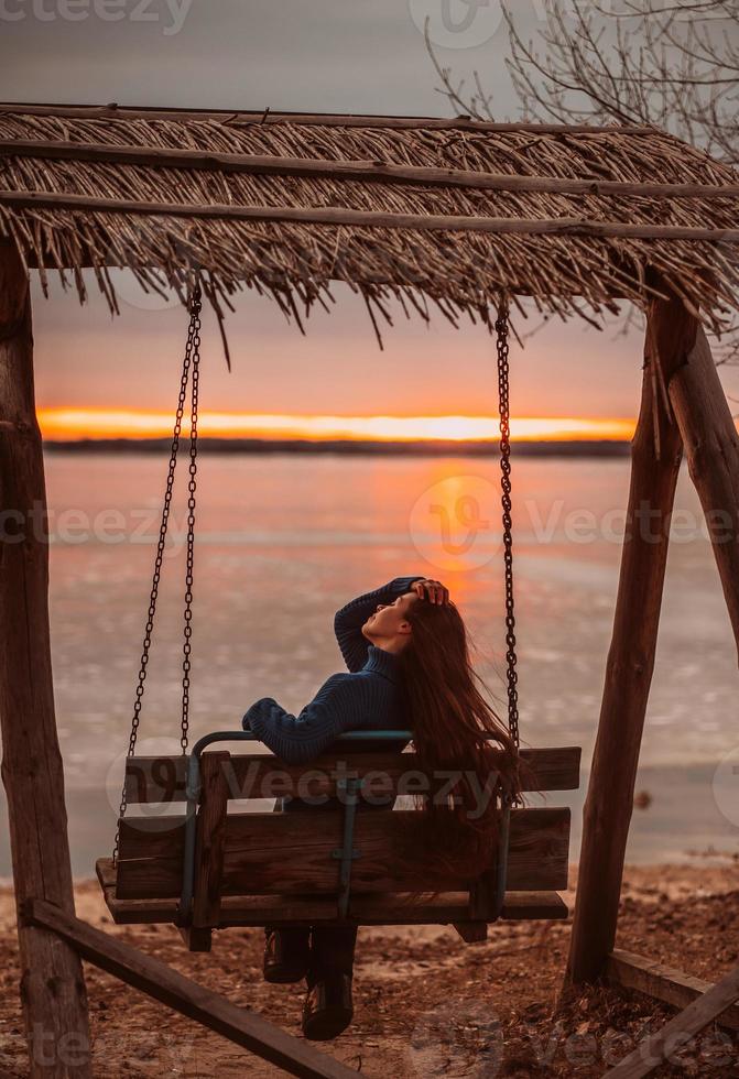 Woman enjoying time relaxing by the beautiful lake at sunrise. photo