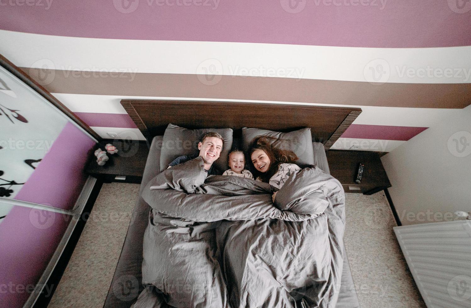 happy child with parents in bed at home photo