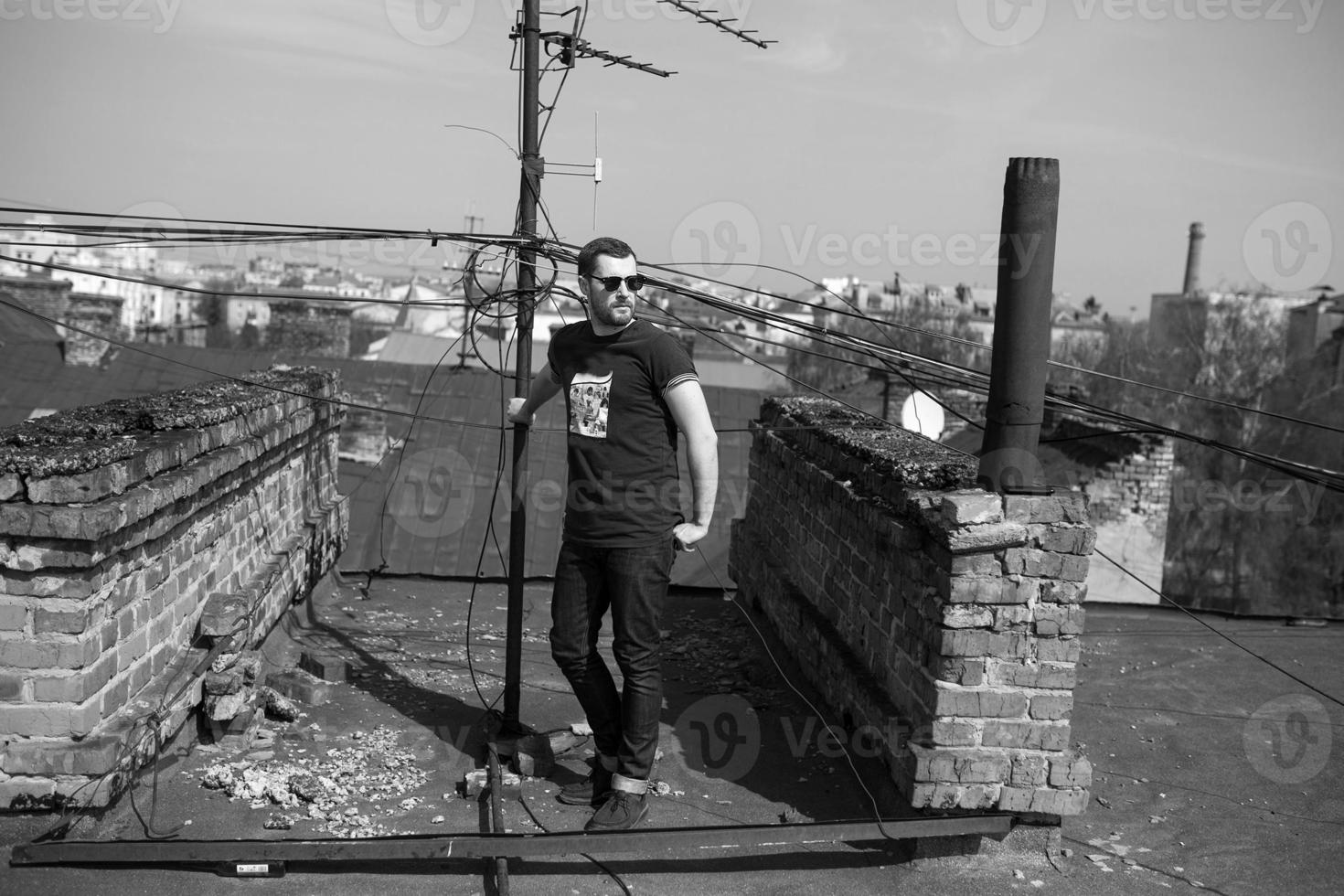 El hombre de las botas auténticas y el orillo de jeans en el techo del edificio en el casco antiguo foto