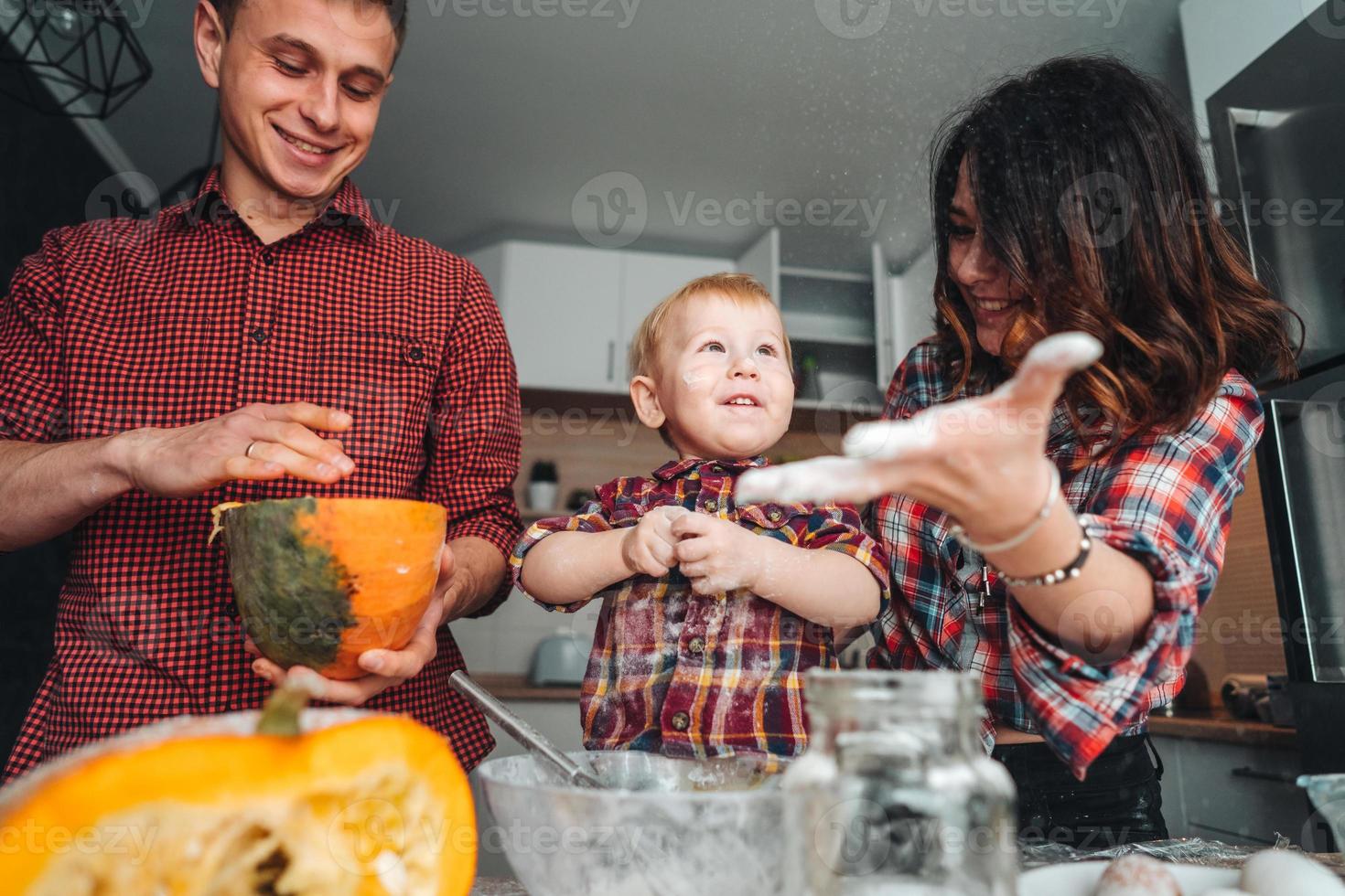 Dad, mom and little son cook a pie photo