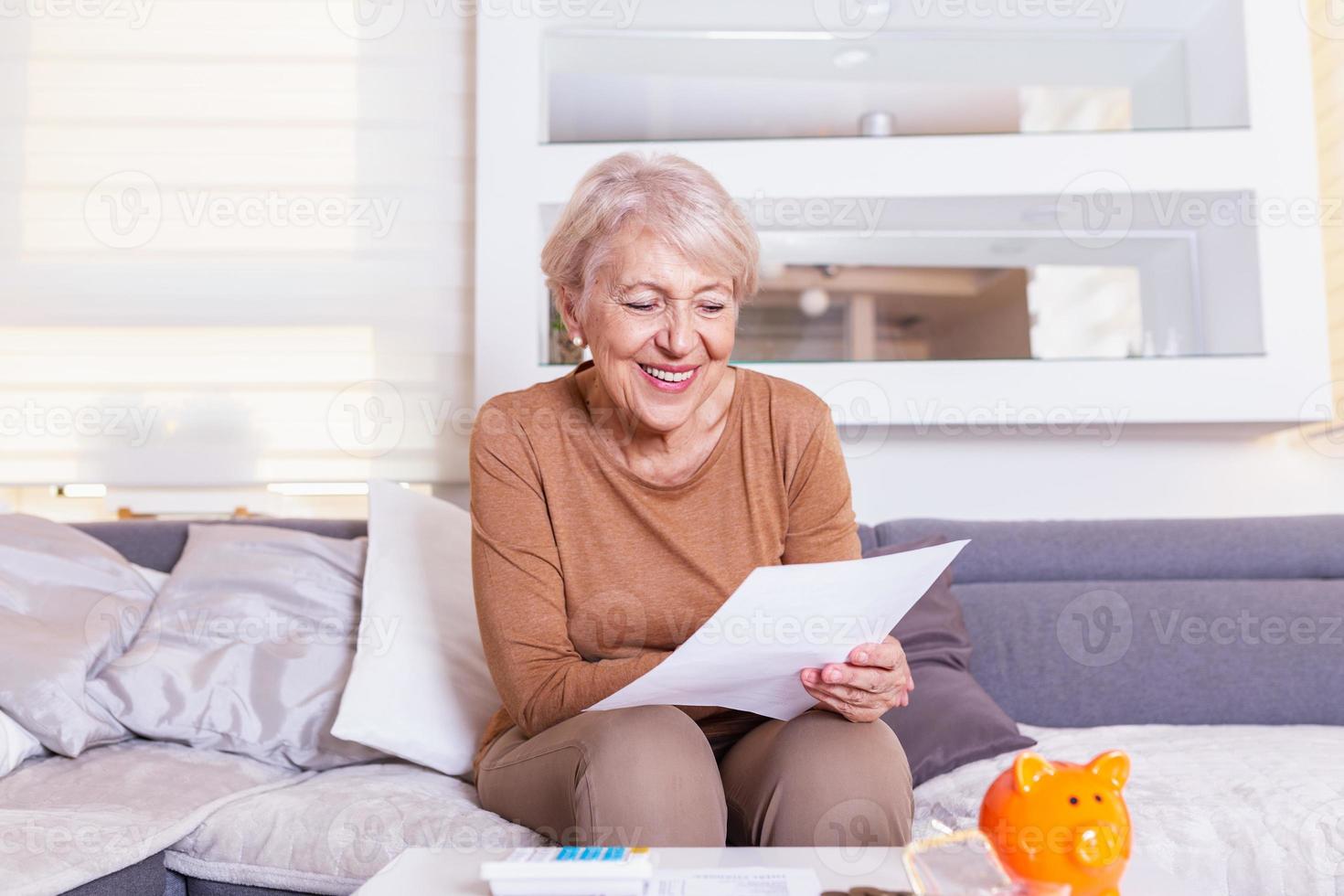 Senior woman smilling and happy about her finances. Old lady receives a letter.Senior lady receiving good news from a paper mail. photo