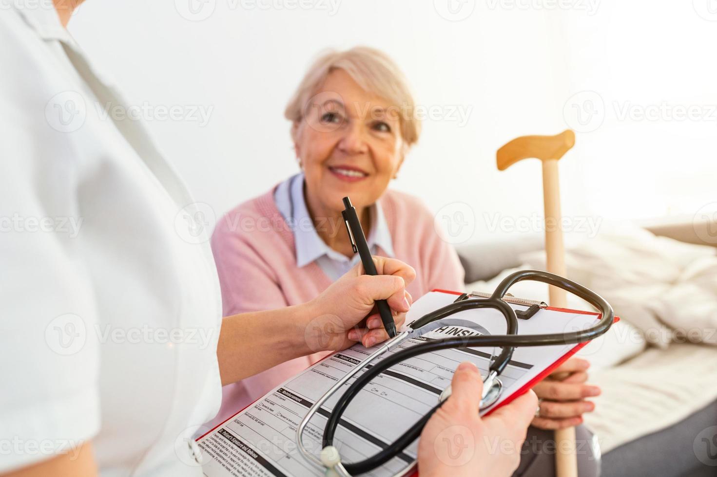 la anciana es visitada por su médico o cuidador. doctora o enfermera hablando con un paciente mayor. concepto de medicina, edad, atención médica y atención domiciliaria. anciana con su cuidadora en casa foto