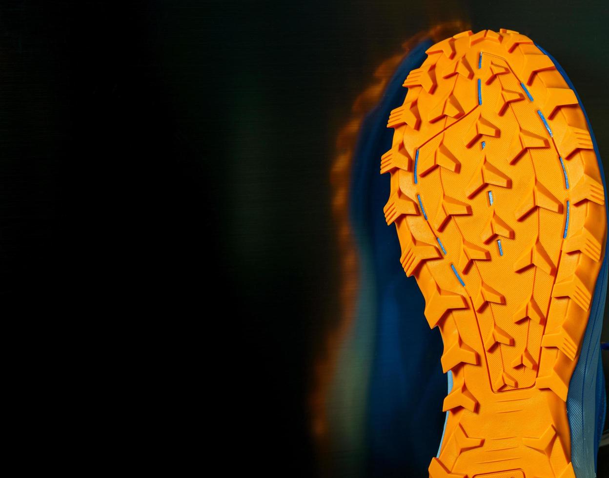 shoes set against a black background, Orange tread sole for trail running. The sole is very thick for wading on smooth roads and muddy roads. photo