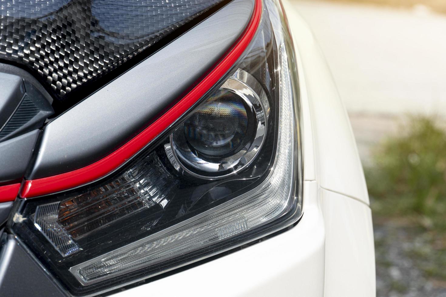 Abstract of luxury or used of headlights of car. Car in the parking lot with blurred of green grass outside at day. photo