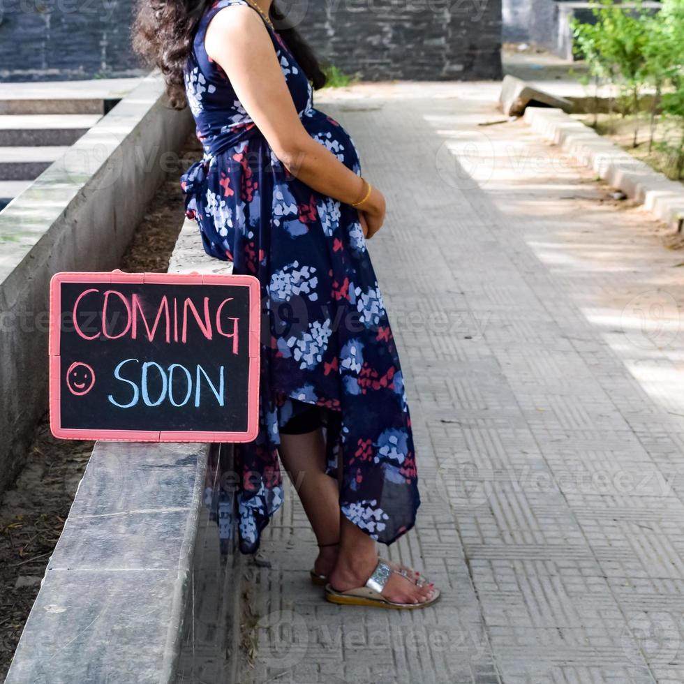 Indian couple posing for maternity baby shoot. The couple is posing in a lawn with green grass and the woman is falunting her baby bump in Lodhi Garden in New Delhi, India photo