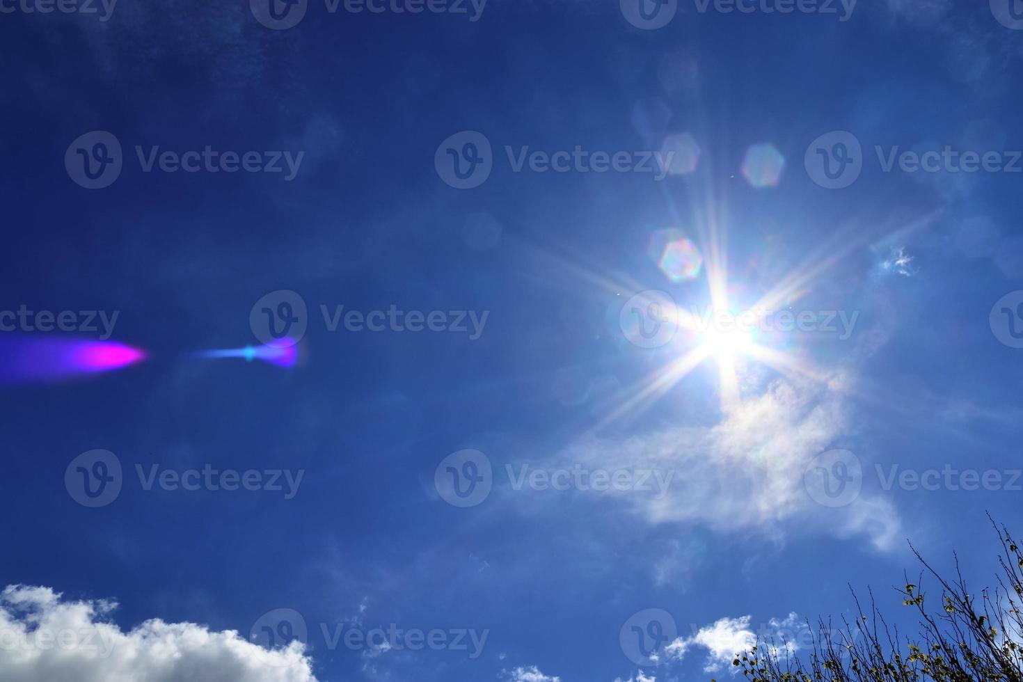 Beautiful view at sunbeams with some lens flares and clouds in a blue sky photo