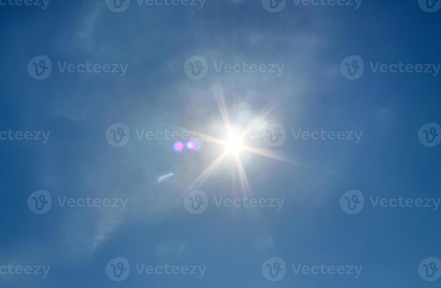 hermosa vista a los rayos de sol con algunas bengalas y nubes en un cielo azul foto