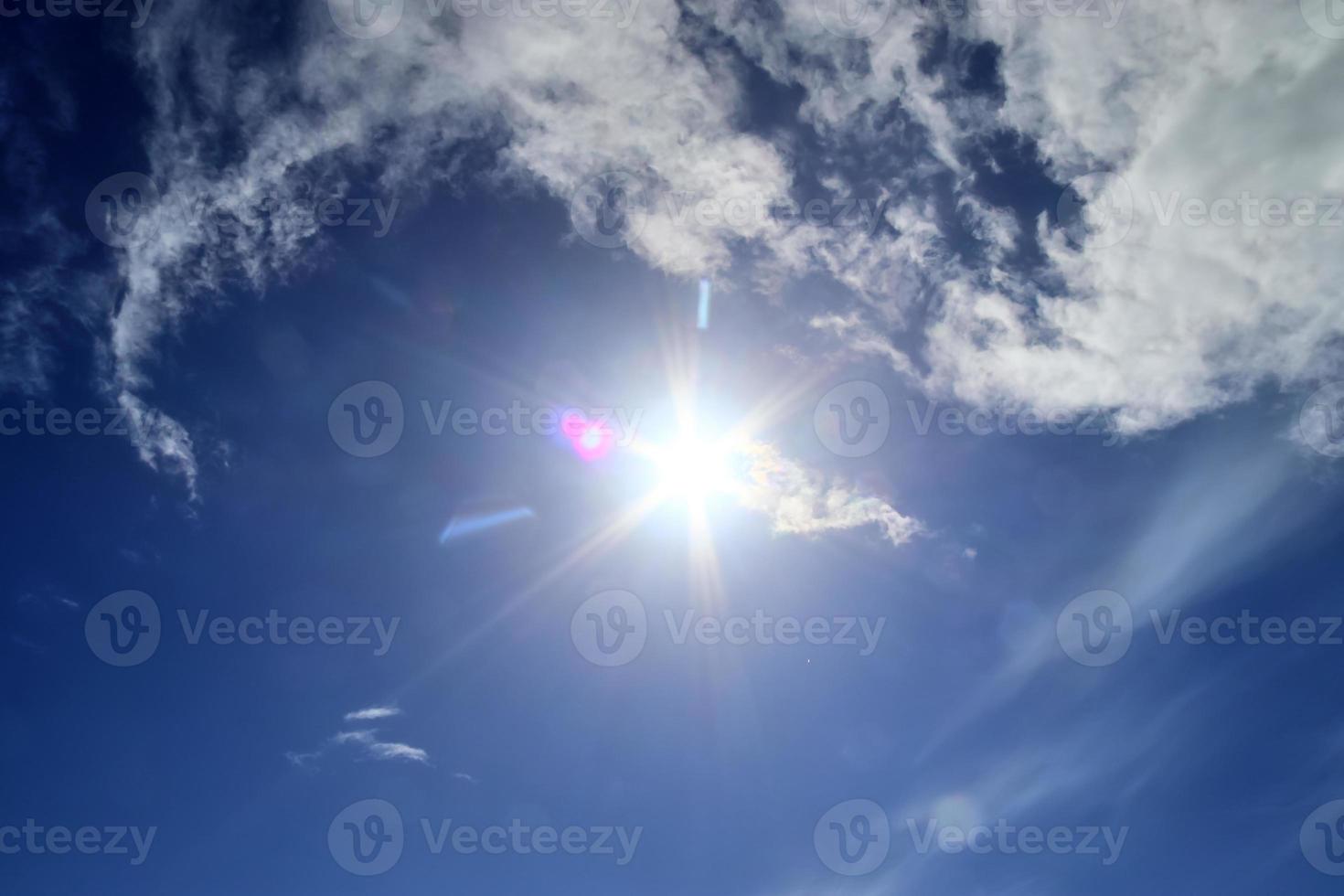 Beautiful view at sunbeams with some lens flares and clouds in a blue sky photo