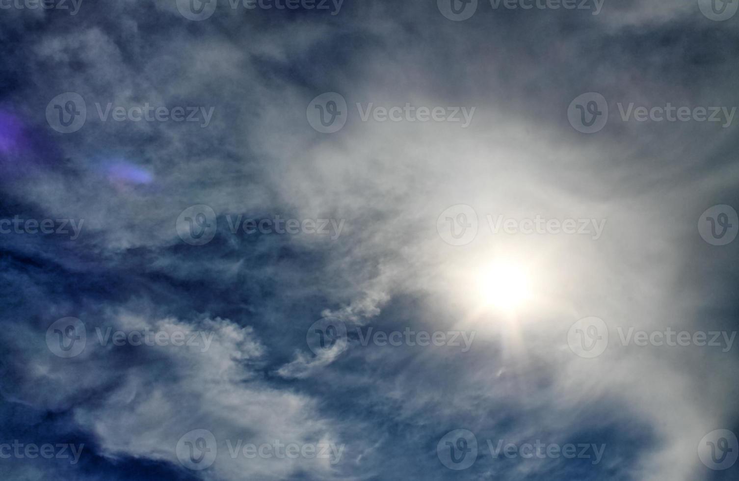 Beautiful view at sunbeams with some lens flares and clouds in a blue sky photo