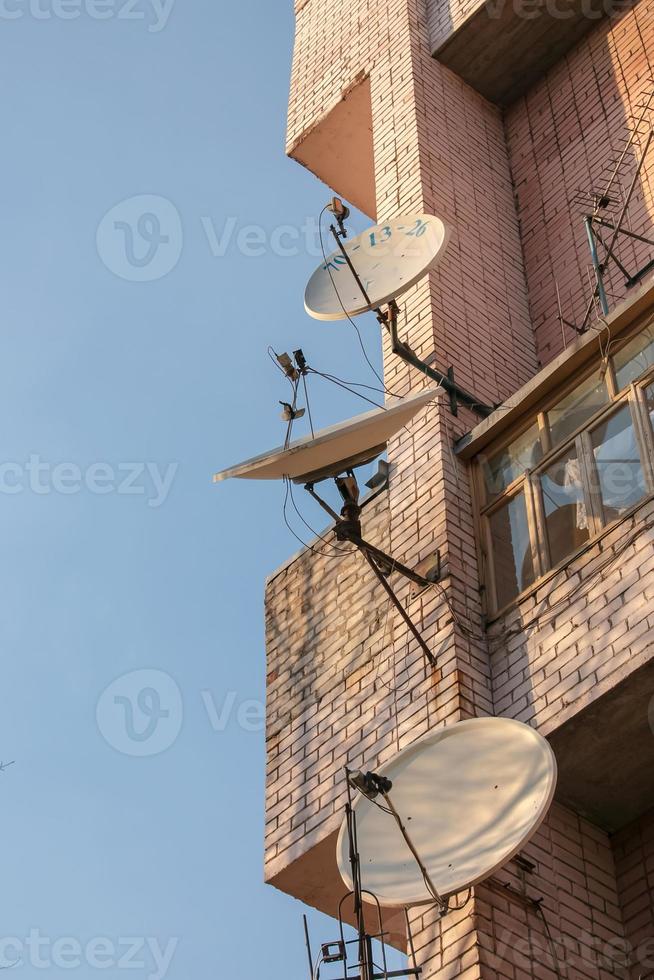 Two old rusty satellite dishes on the wall of the house photo