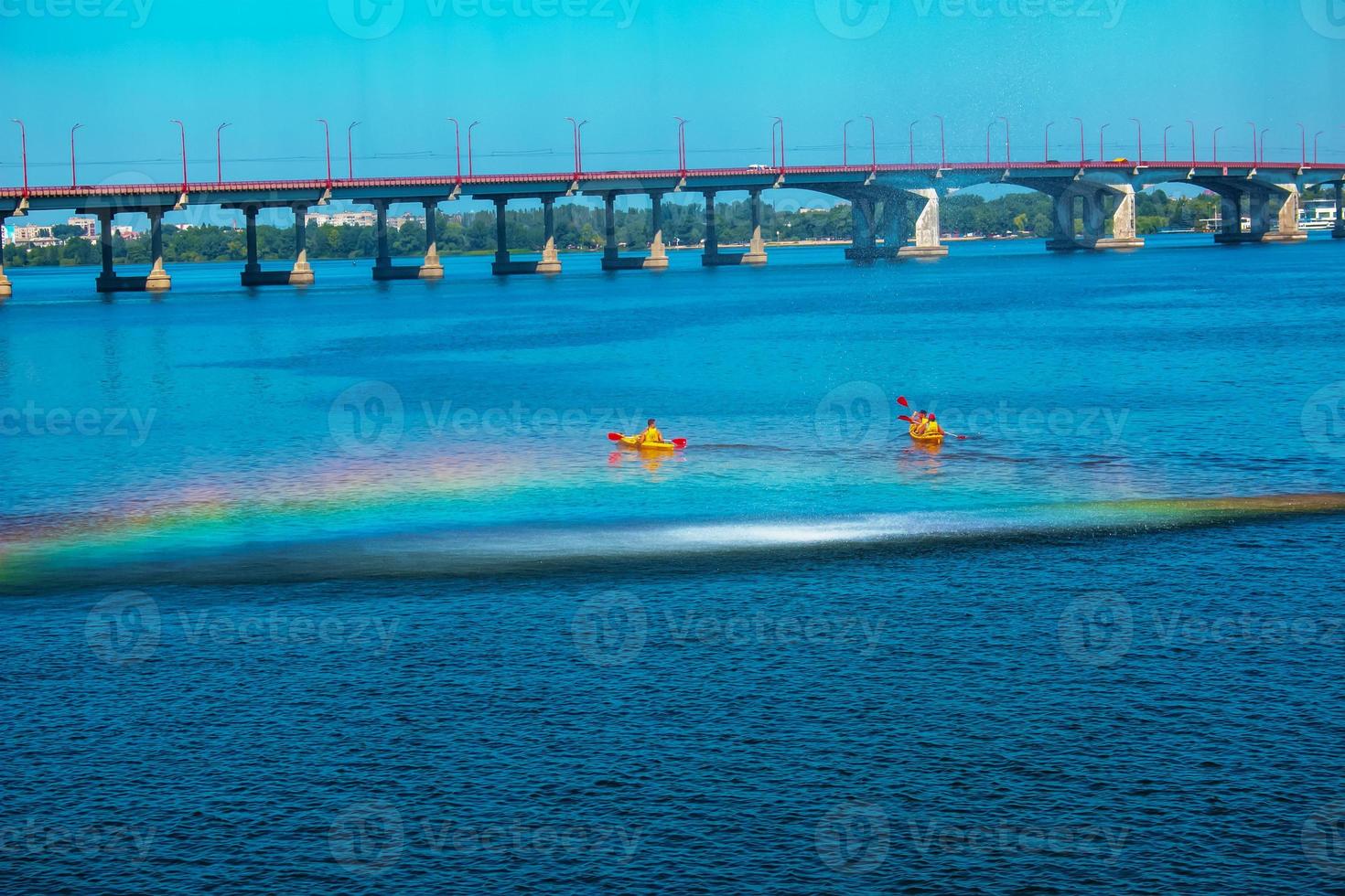 Athletes in kayaks in training near the river fountain in a rainbow of splashes. photo