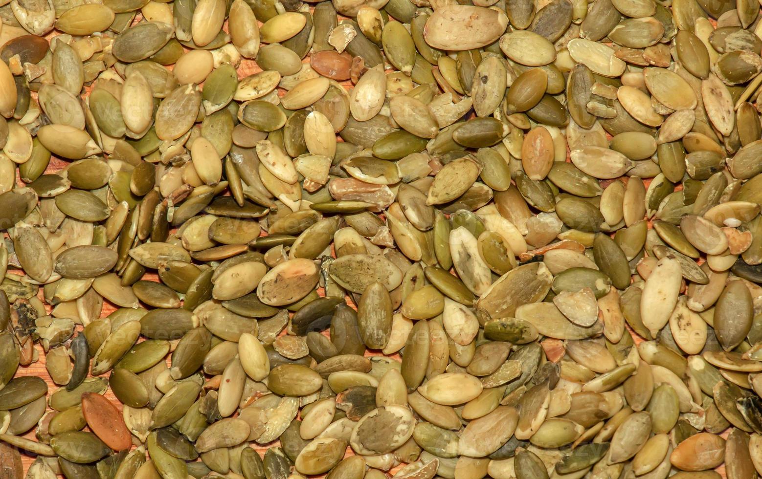 Close-up background texture of green roasted pumpkin seeds. Peeled pumpkin seeds background photo