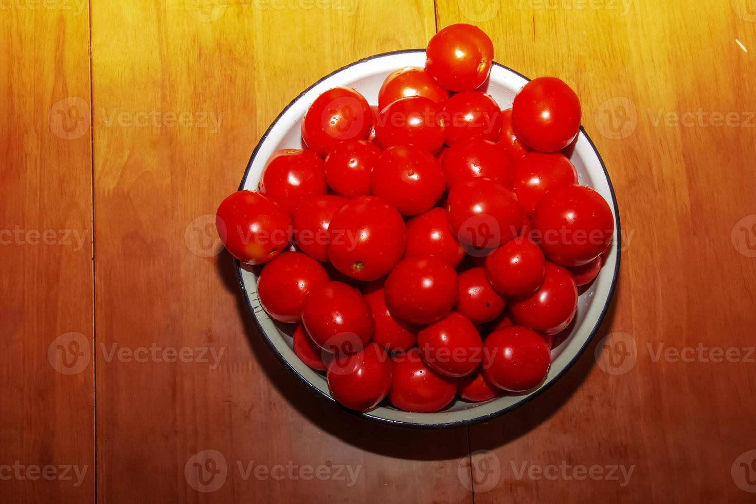 Bowl with ripe red freshly washed tomatoes on a brown background. photo