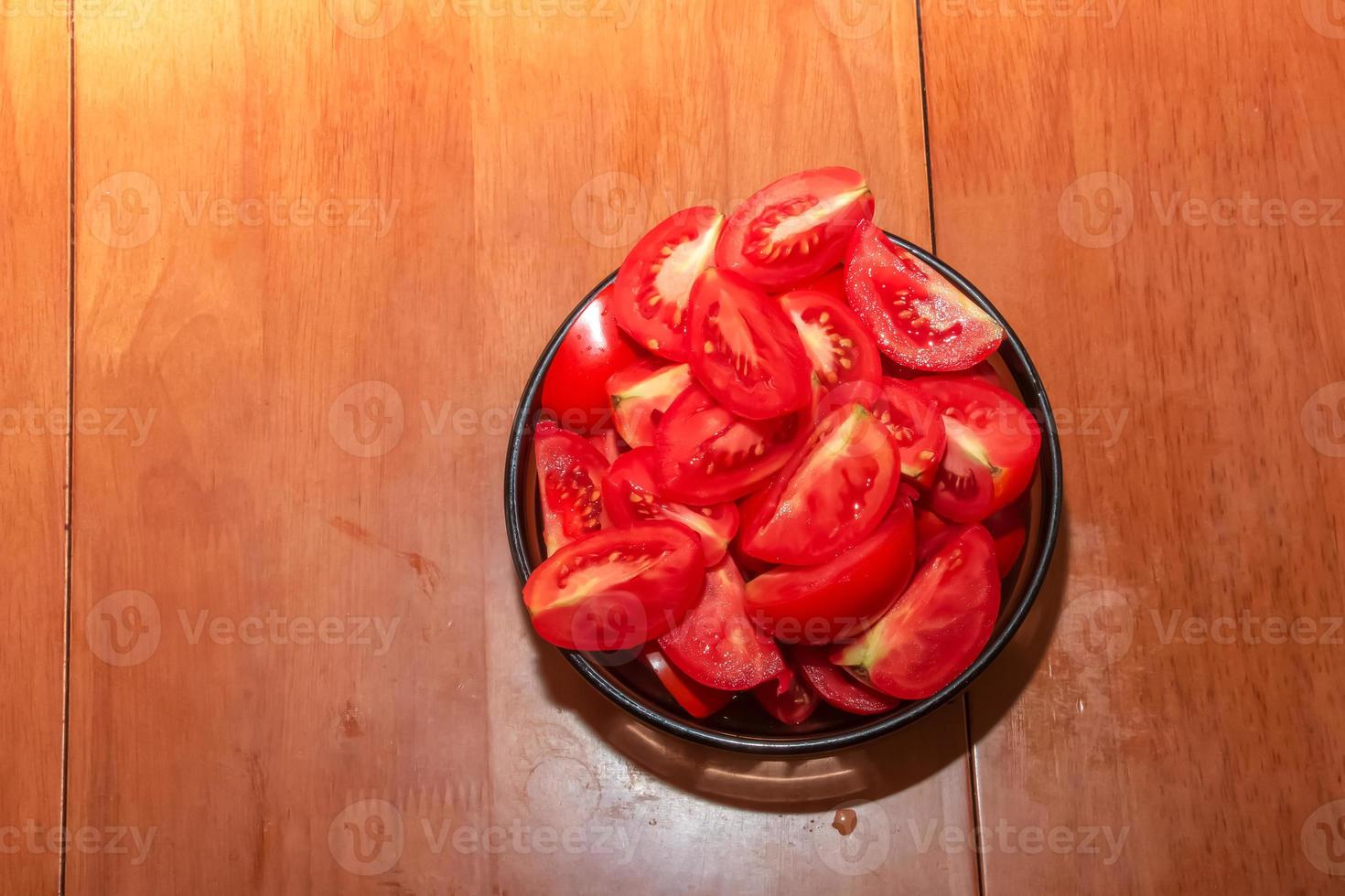 Bowl with ripe red freshly washed chopped tomatoes on a brown background. photo