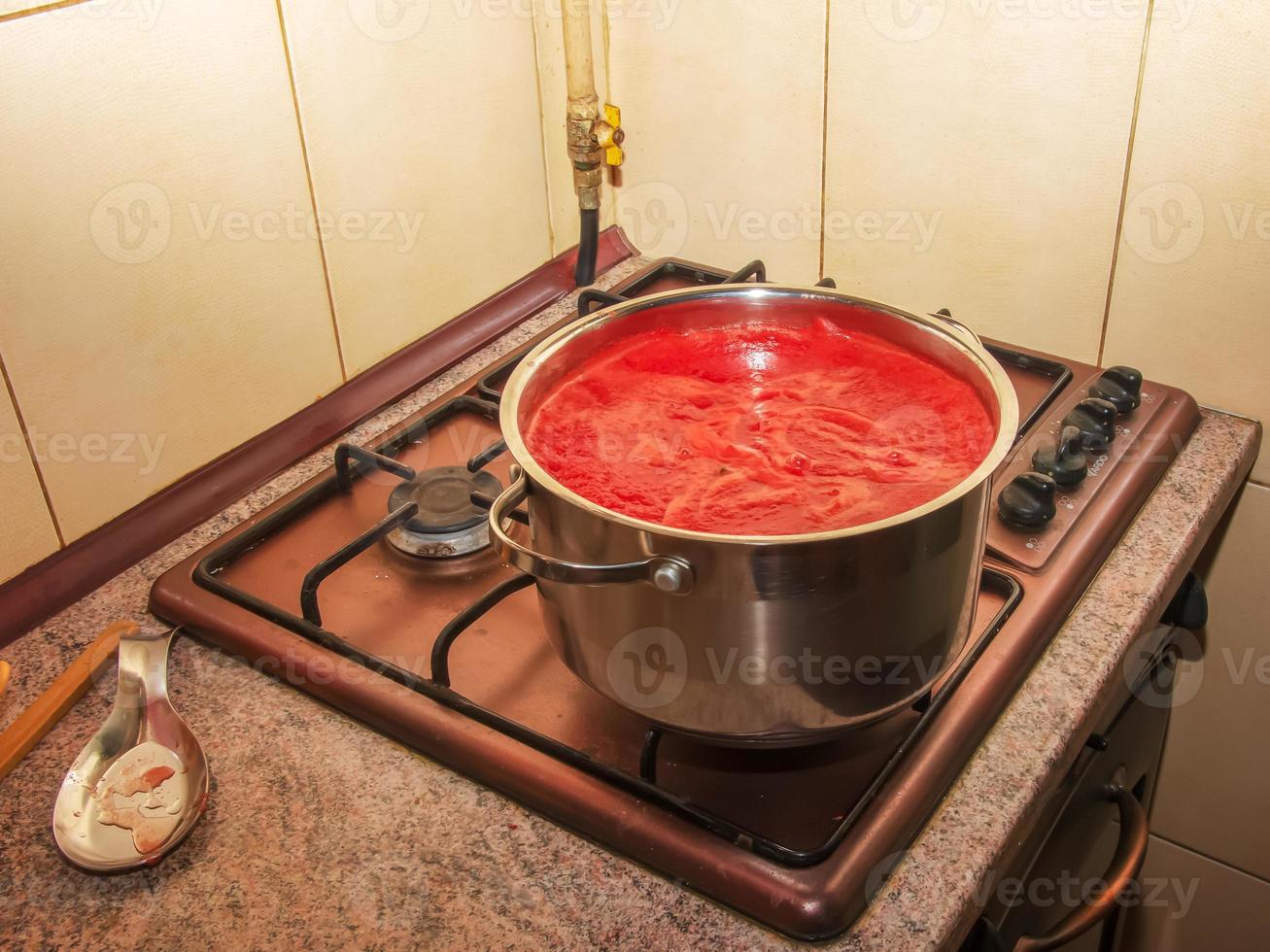 una mujer prepara jugo fresco y saludable de tomates. El jugo de tomate recién hecho se hierve en una cacerola y se conserva para almacenamiento a largo plazo. concepto de dieta para un estilo de vida saludable. foto