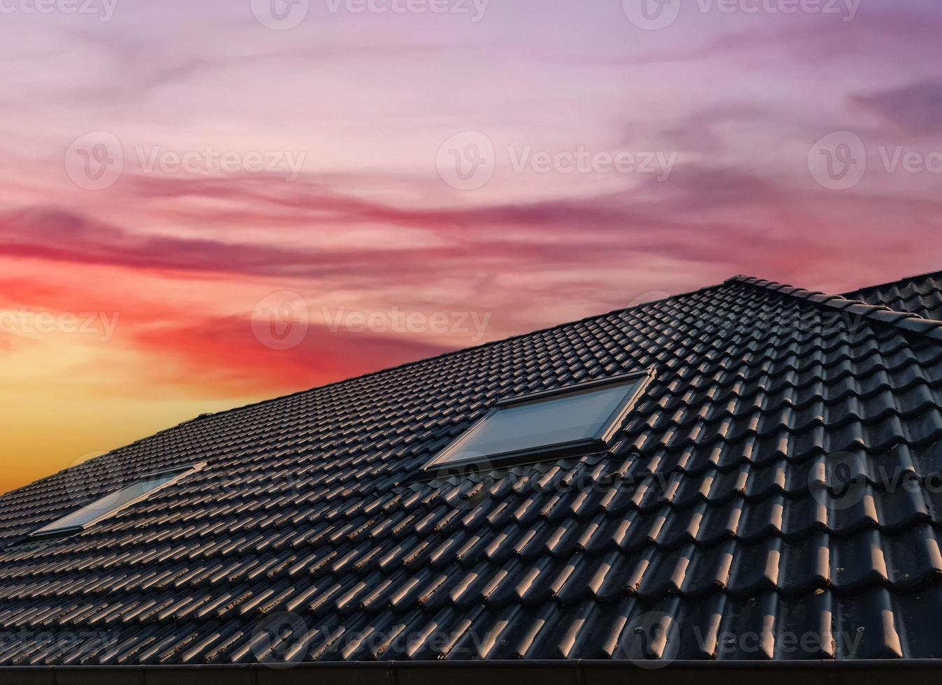 Open roof window in velux style with black roof tiles during sunset. photo