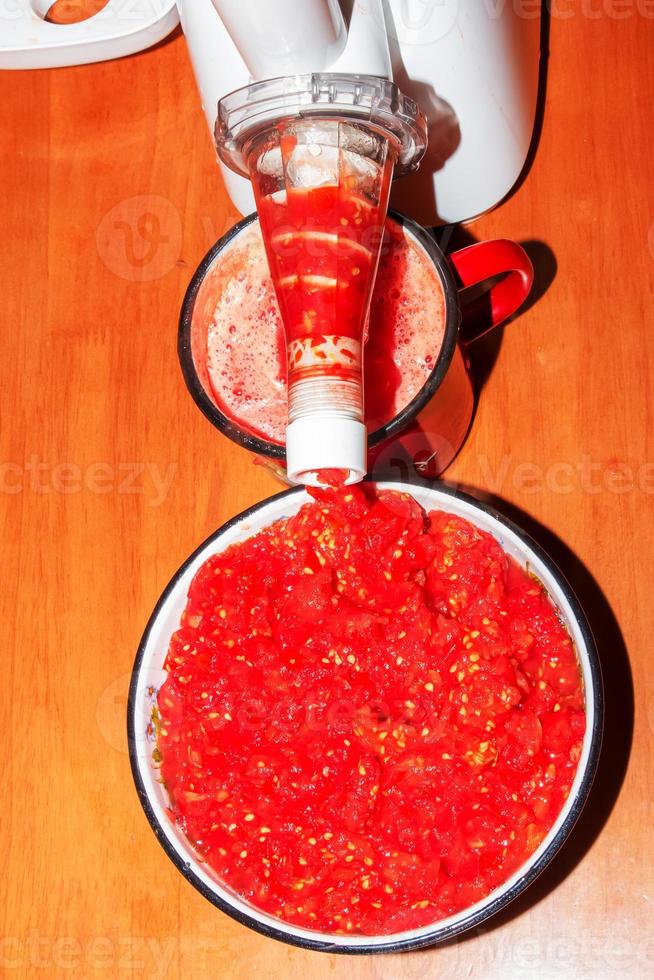 A woman prepares fresh healthy juice from tomatoes. Juicer at work