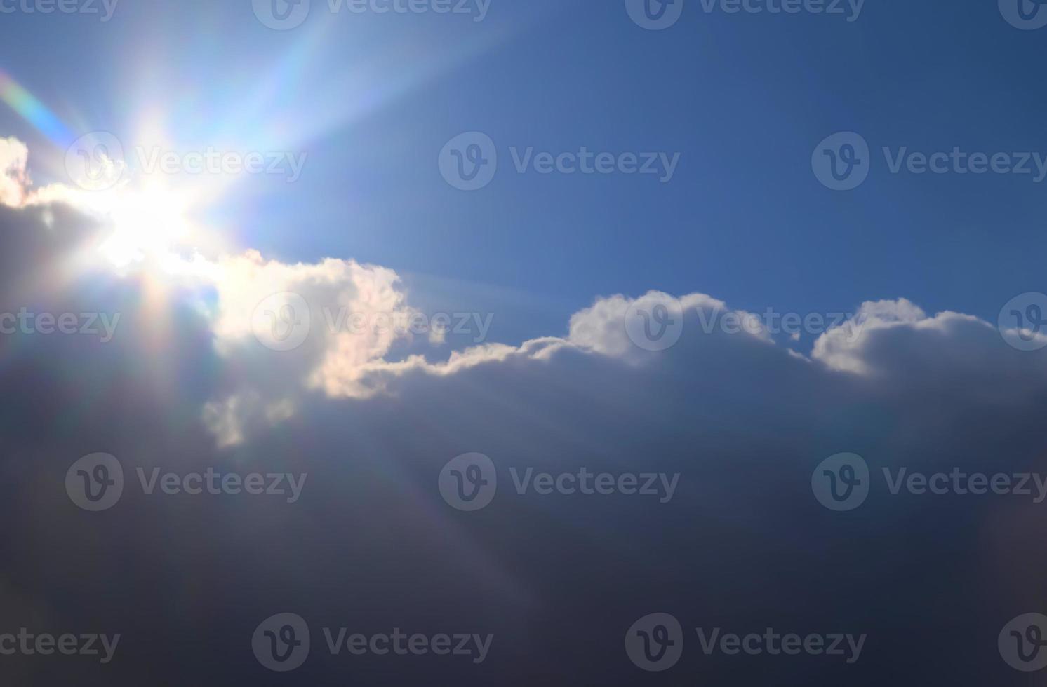 hermosa vista a los rayos de sol con algunas bengalas y nubes en un cielo azul foto