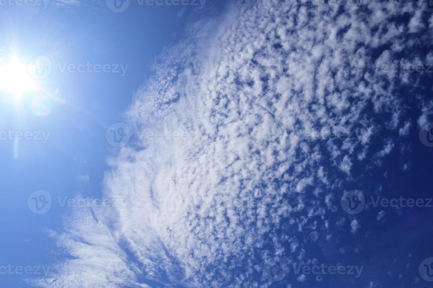 hermosa vista a los rayos de sol con algunas bengalas y nubes en un cielo azul foto