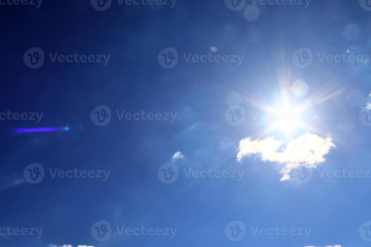 hermosa vista a los rayos de sol con algunas bengalas y nubes en un cielo azul foto