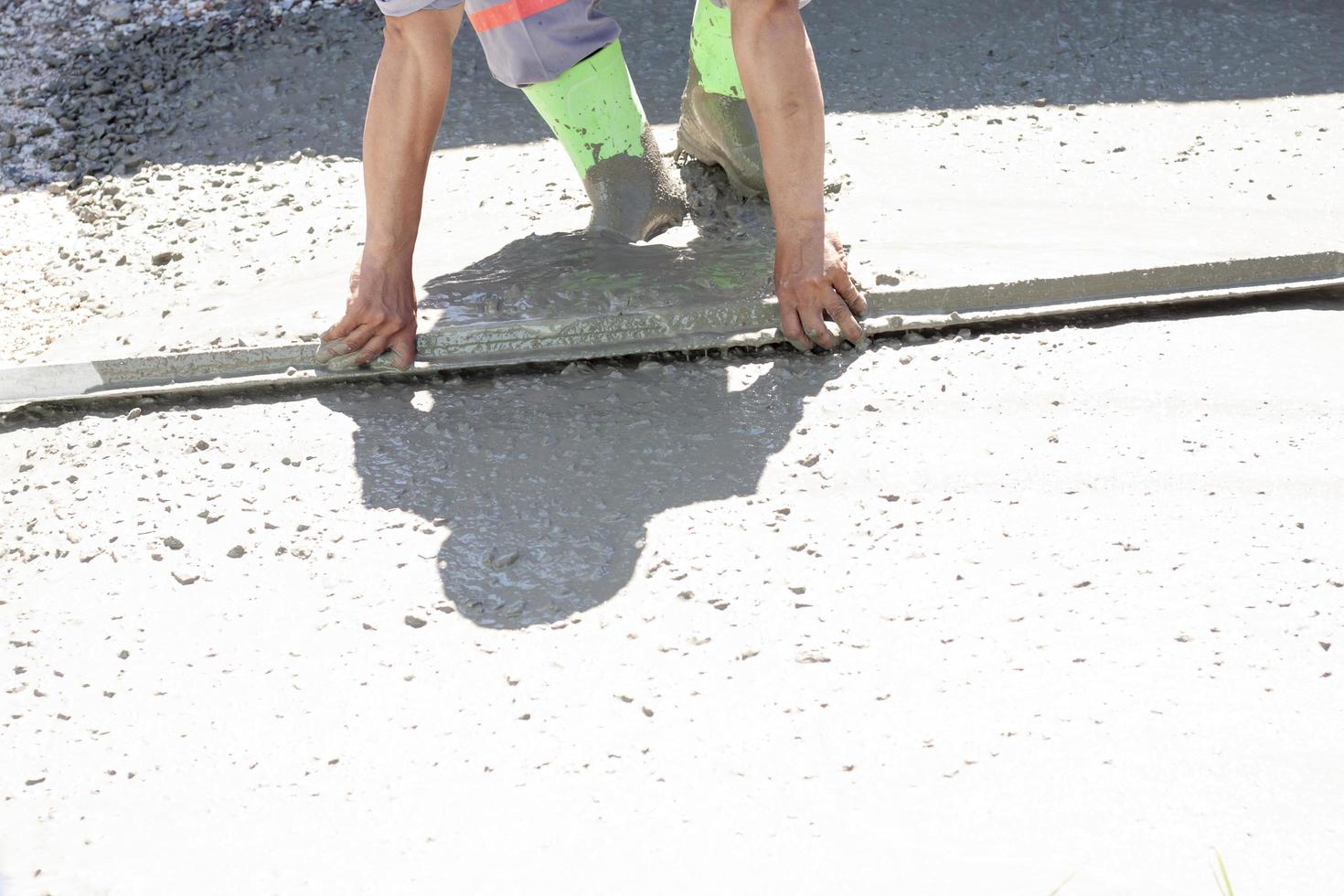 Construction workers are working by leveling the concrete floor smooth in the heat of the sun. photo