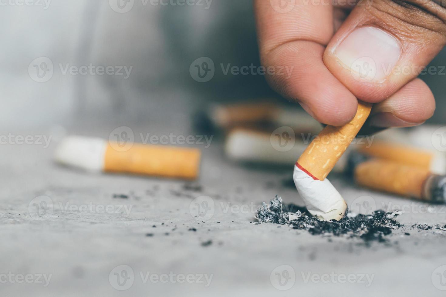 mano apagando un cigarrillo, colilla de cigarrillo en el piso de concreto, cemento desnudo. foto