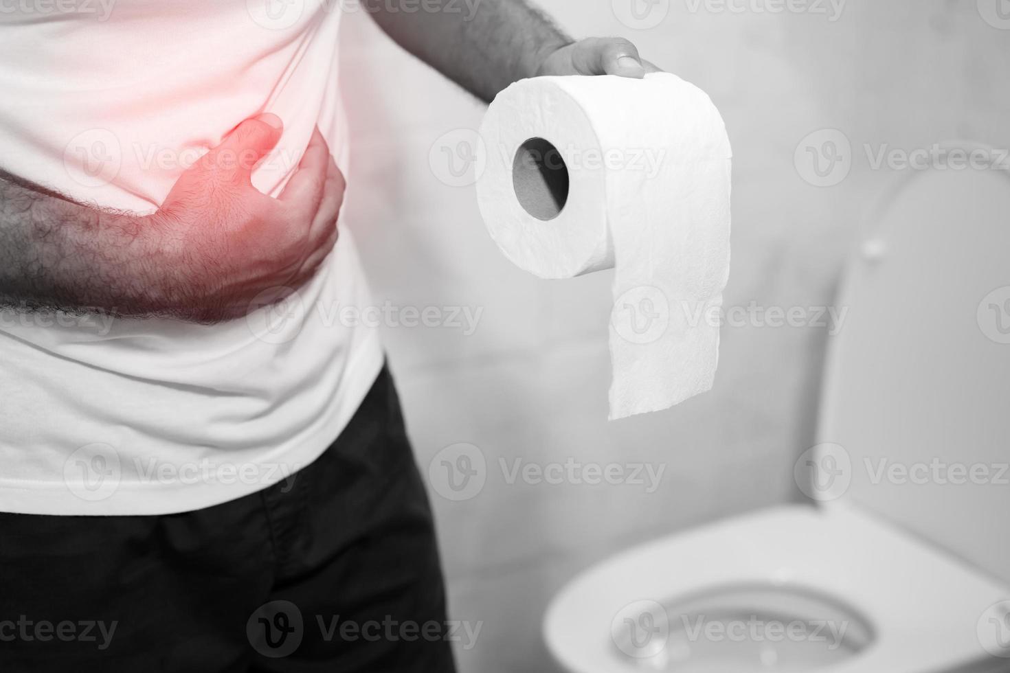 Man suffers from diarrhea hand hold tissue paper roll in front of toilet bowl. constipation in bathroom. Treatment stomach pain and Hygiene, health care photo