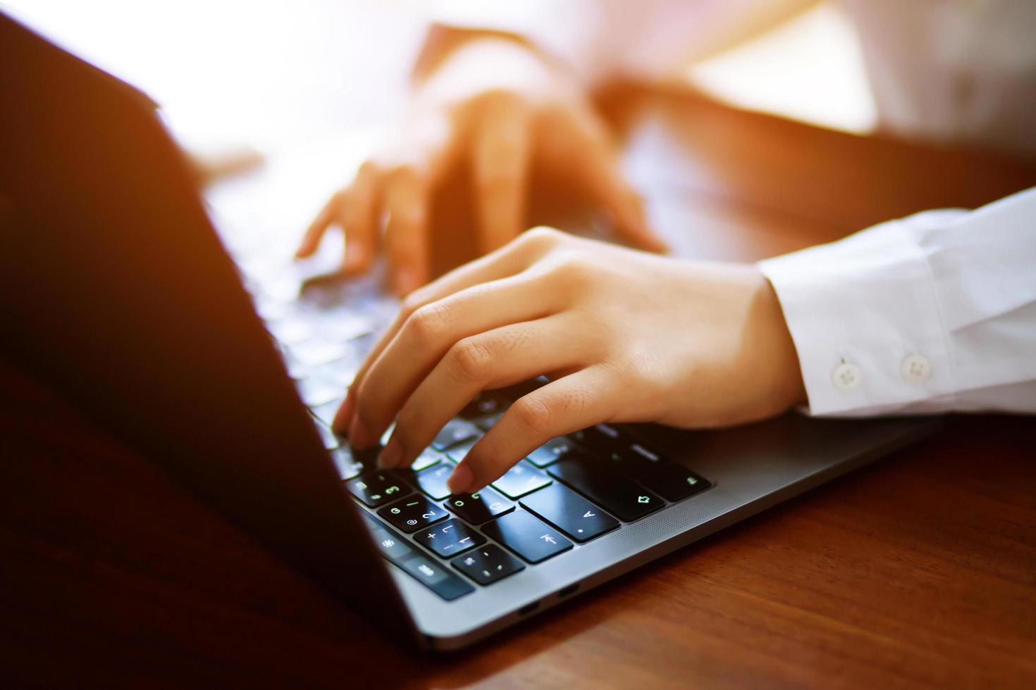 mujer de negocios independiente sentada usando su computadora portátil y su teléfono inteligente móvil envía trabajo con una taza de café en la mesa de madera en una cafetería. mujer trabajadora. foto