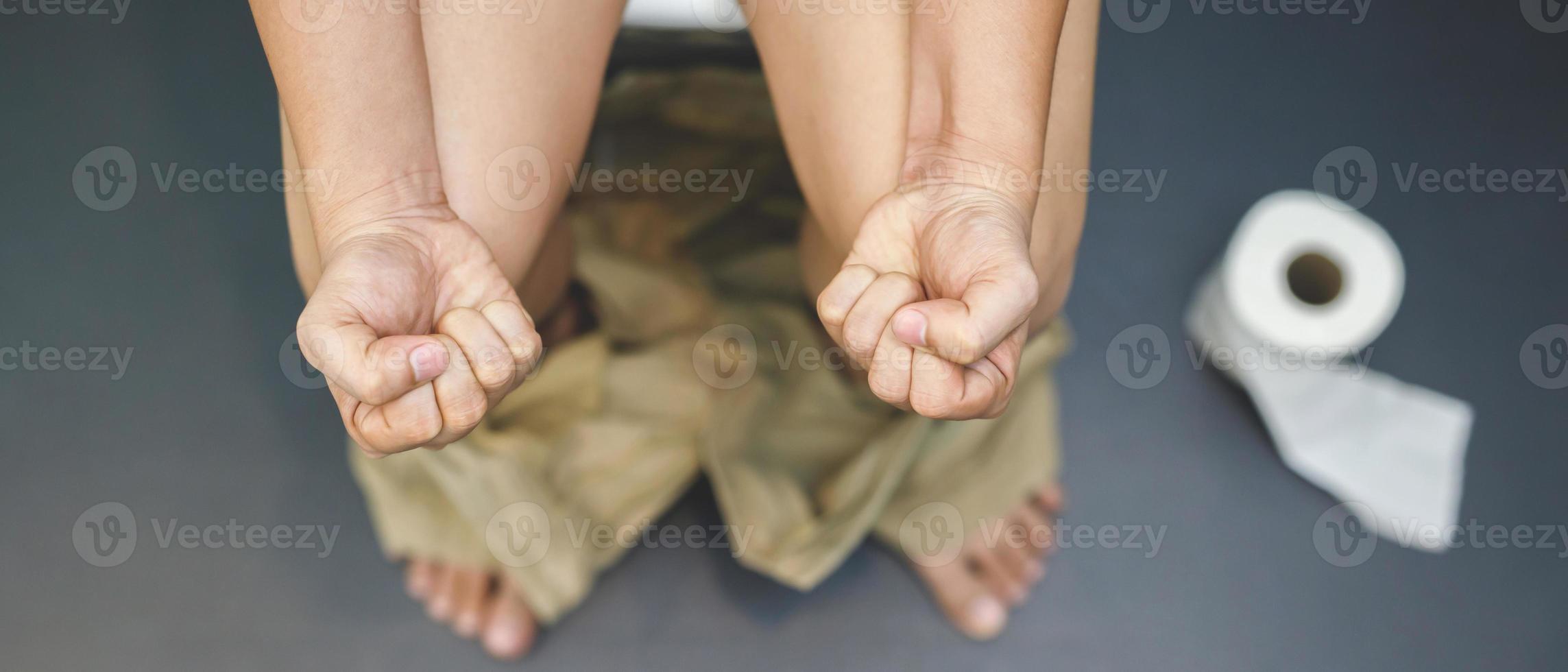 Man suffers from diarrhea hand hold tissue paper roll in front of toilet bowl. constipation in bathroom. Treatment stomach pain and Hygiene, health care photo