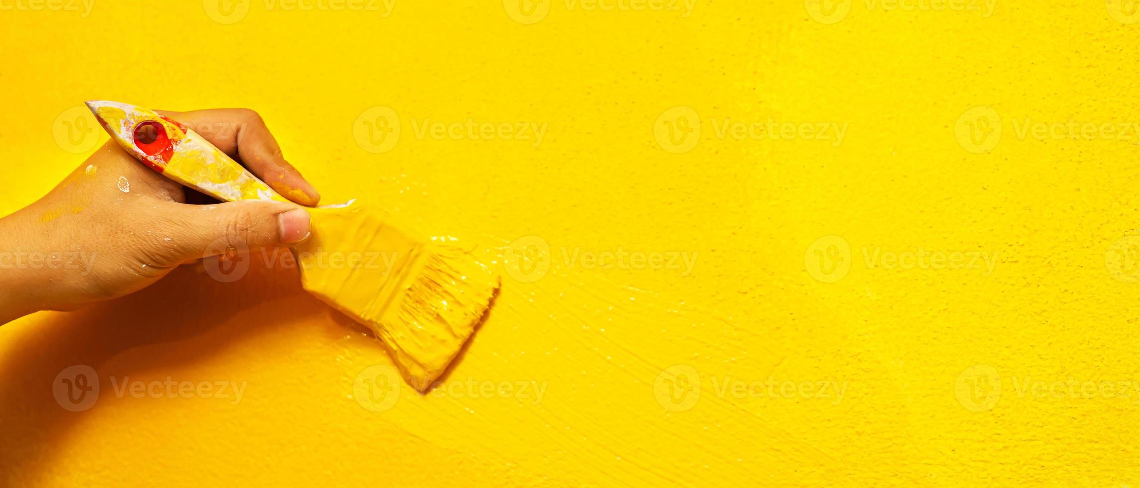 Painter is painting the interior wall yellow photo