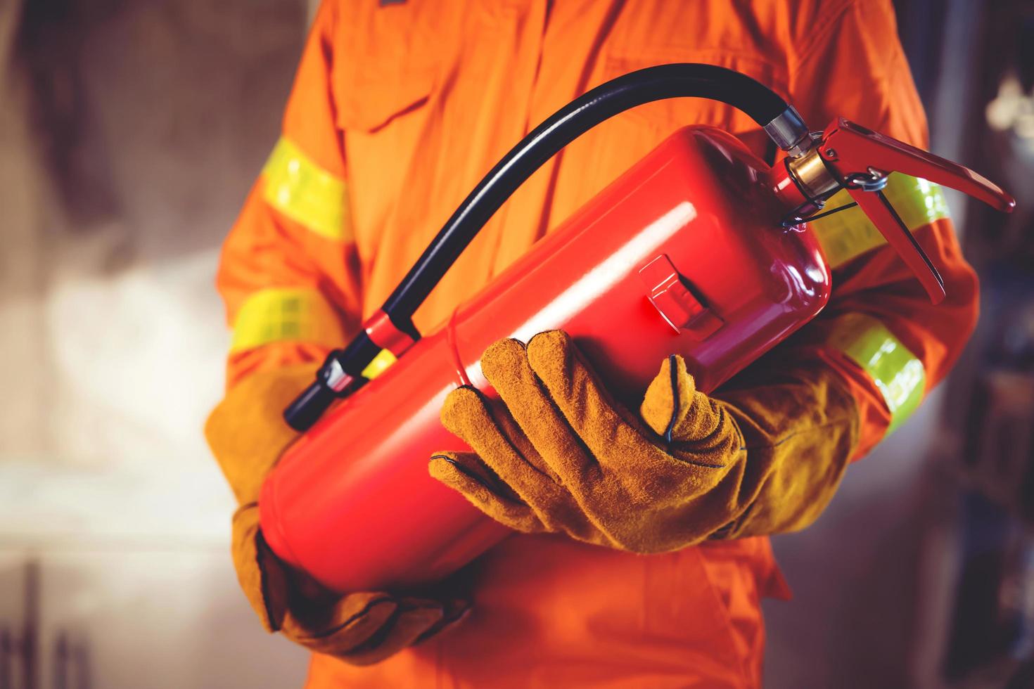 Fireman hand holding fire extinguisher. available in emergencies conflagration damage background. Safety concept. photo