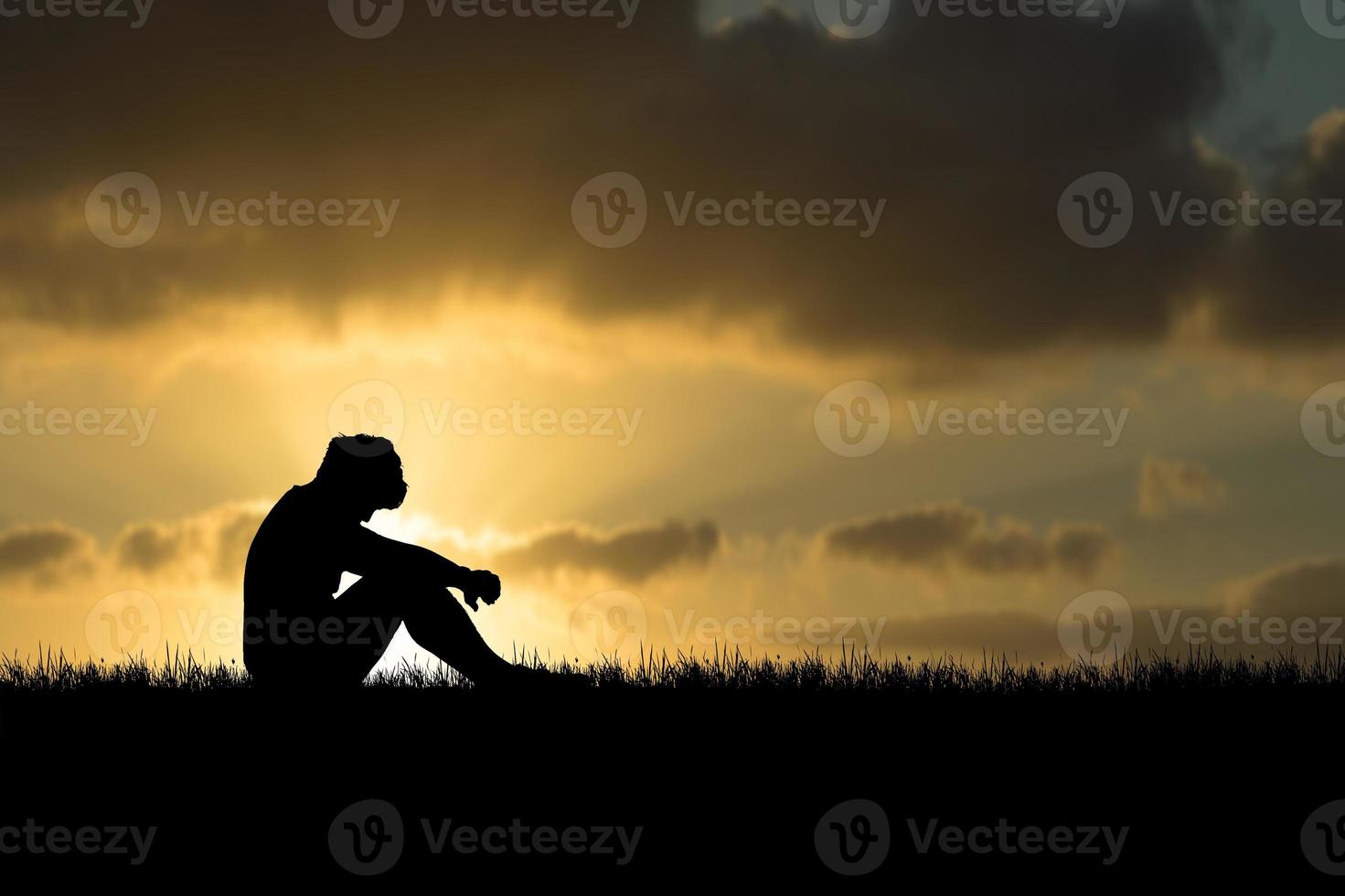 The concept of despair, discouragement, and loneliness. Silhouettes of people sitting with their heads down in sorrow in the meadows. photo