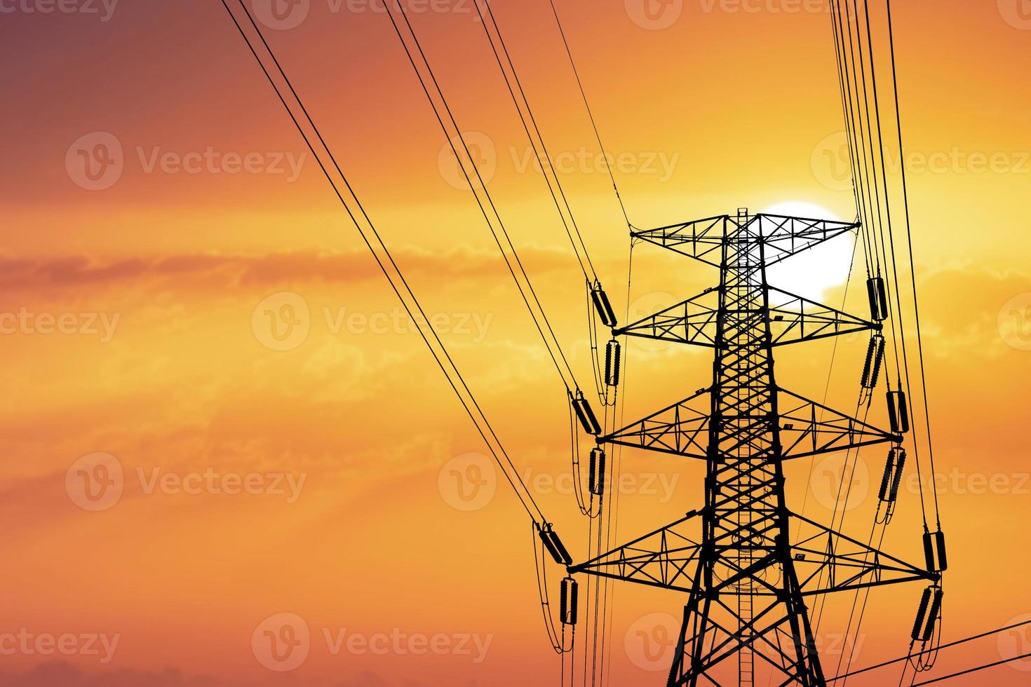 Silhouette of high voltage poles with electric wires. Silhouette of high voltage power line cables in an orange evening sunset. Steel structure of electric poles. electric power transmission concept photo