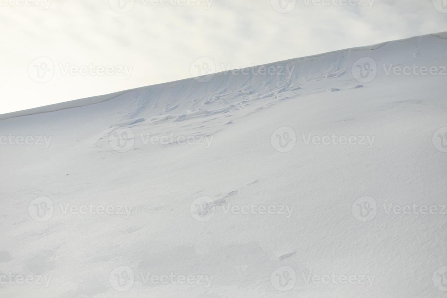 pendiente nevada contra el cielo. avalancha de nieve en la cresta de la montaña. clima invernal. foto