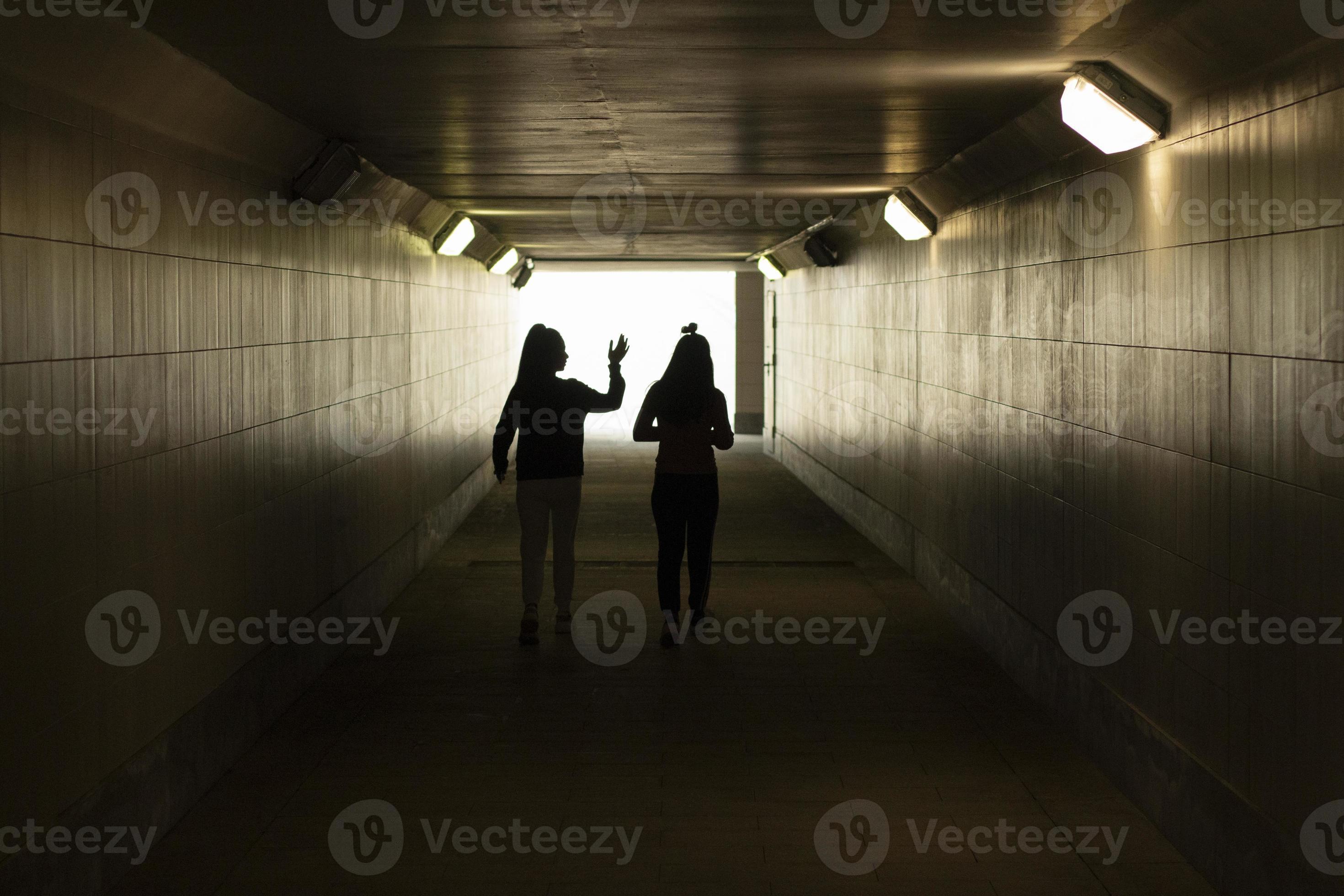 Silhouette of people in the tunnel. The girls walk through an