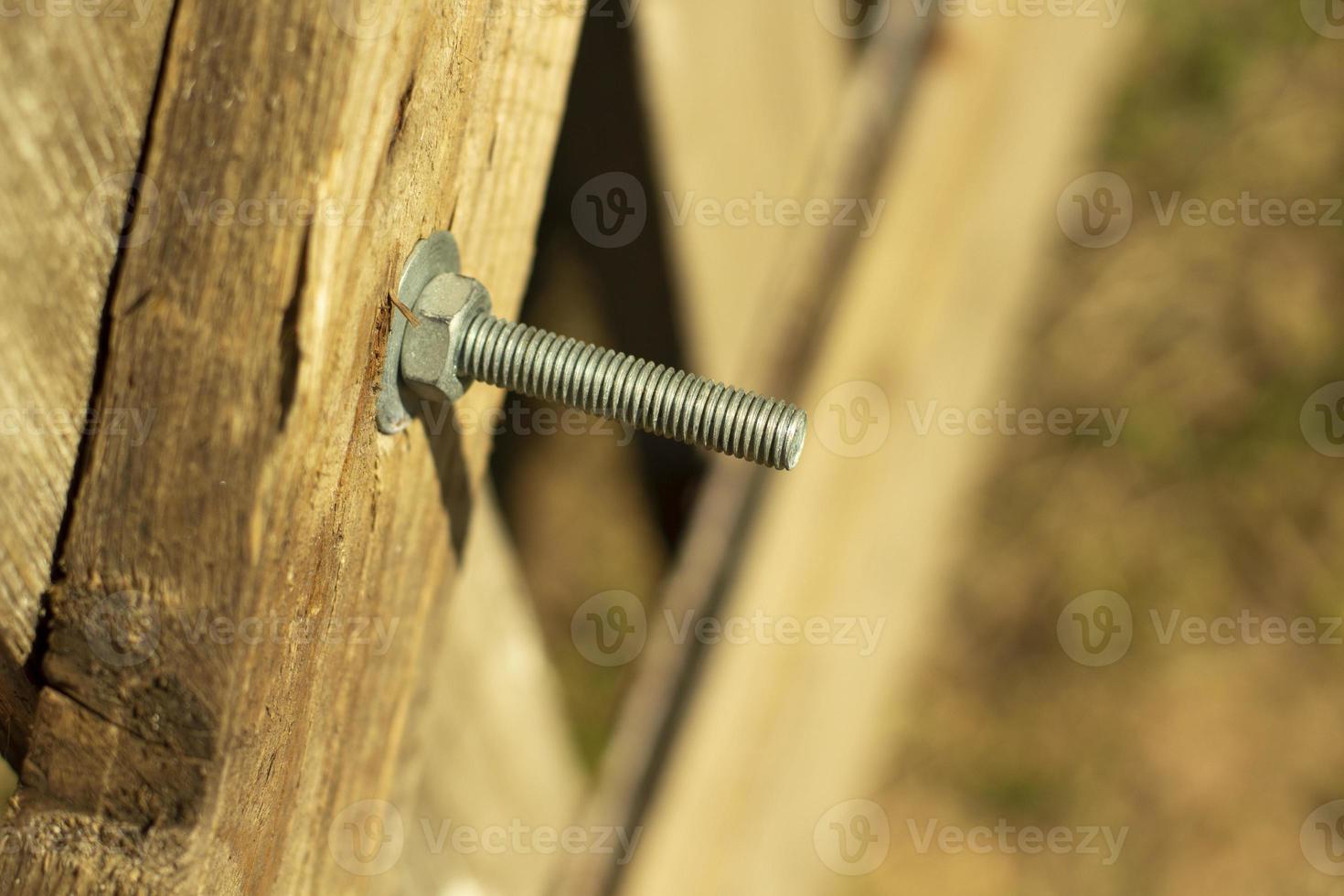 Bolt screwed into the board. Thread on the bolt. The nut is twisted on the thread. Fastening the board to the board. photo