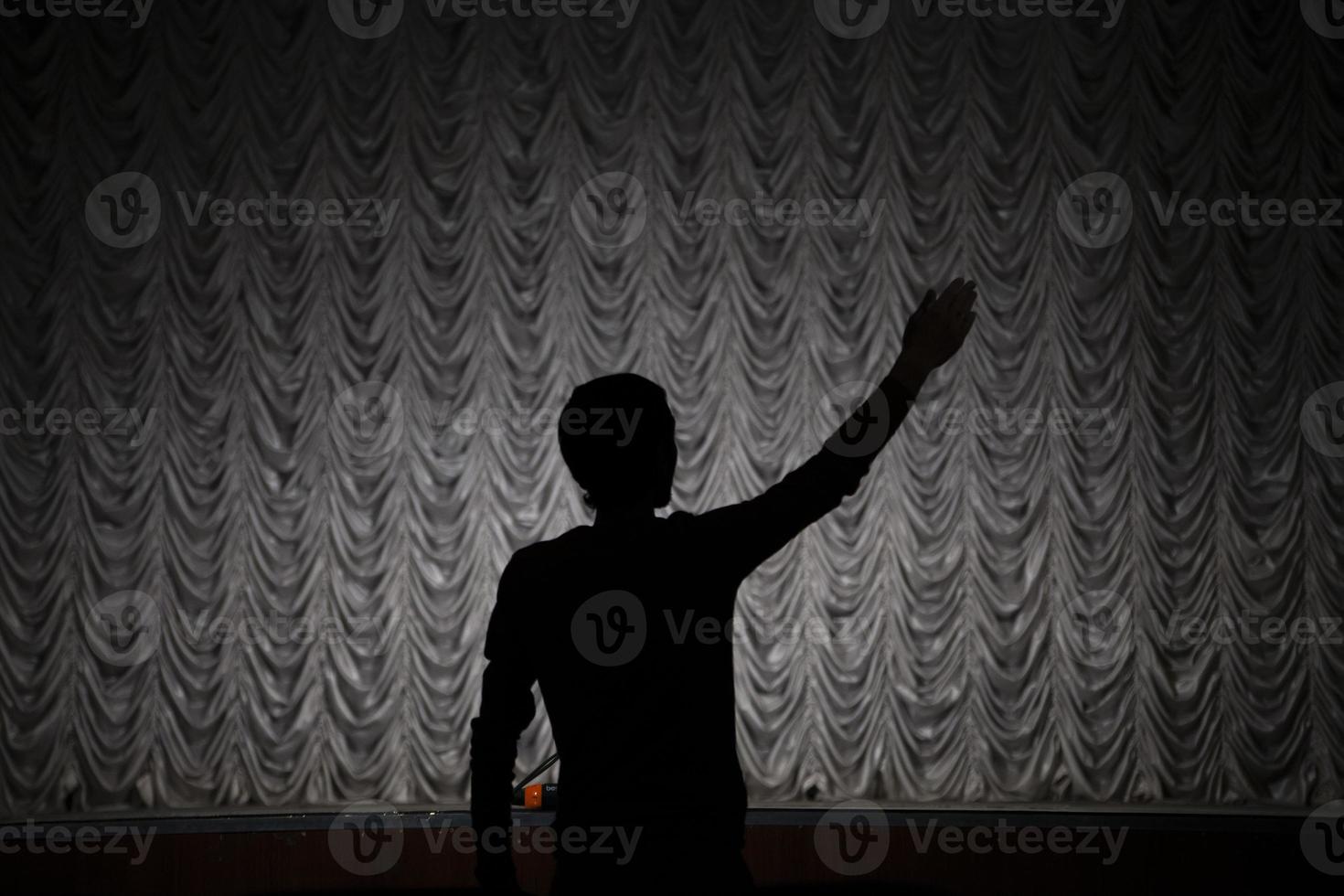 Silhouette of the director. A man directs a play. Hand gesture. photo