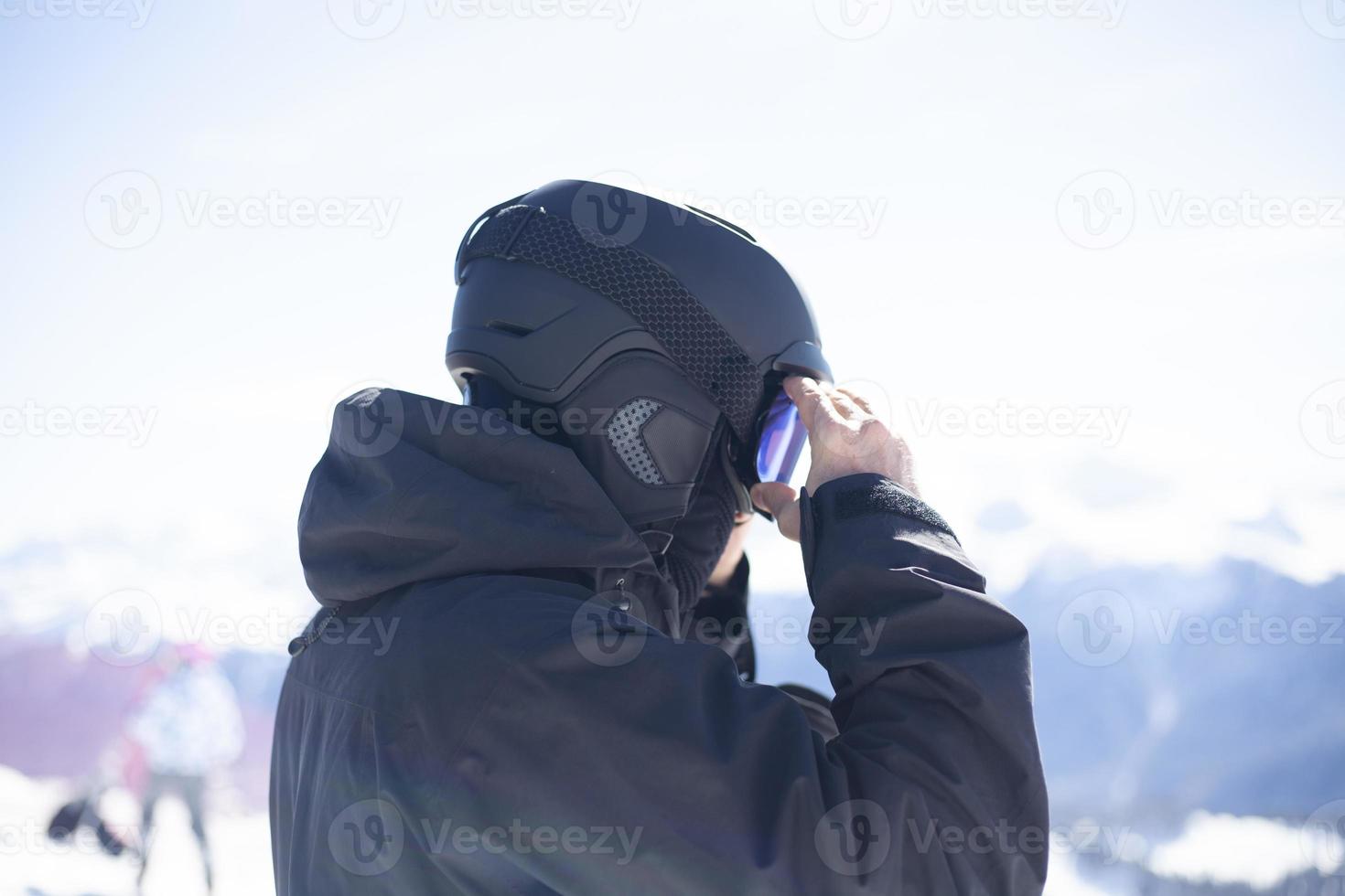 Snowboarder straightens his helmet photo