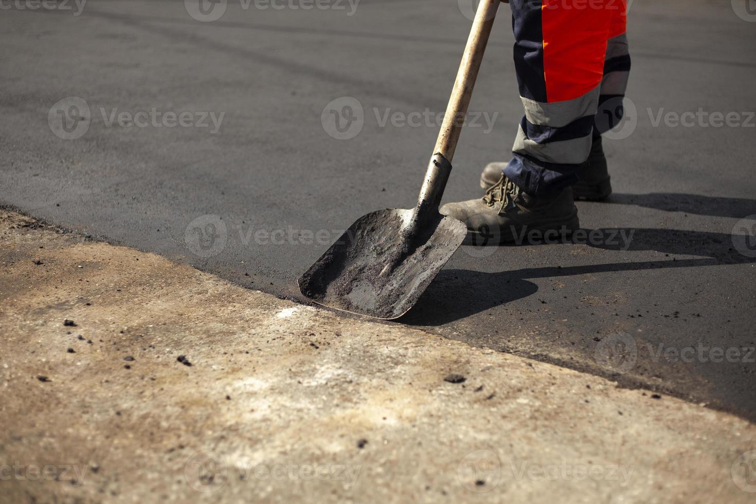 A worker with a shovel is laying asphalt. photo