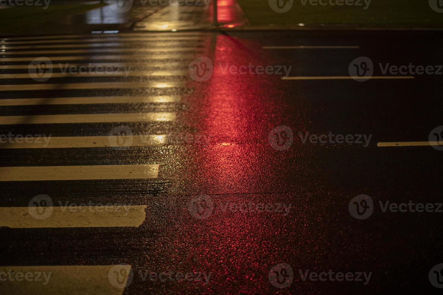 el color rojo del semáforo se refleja en el paso de peatones. foto
