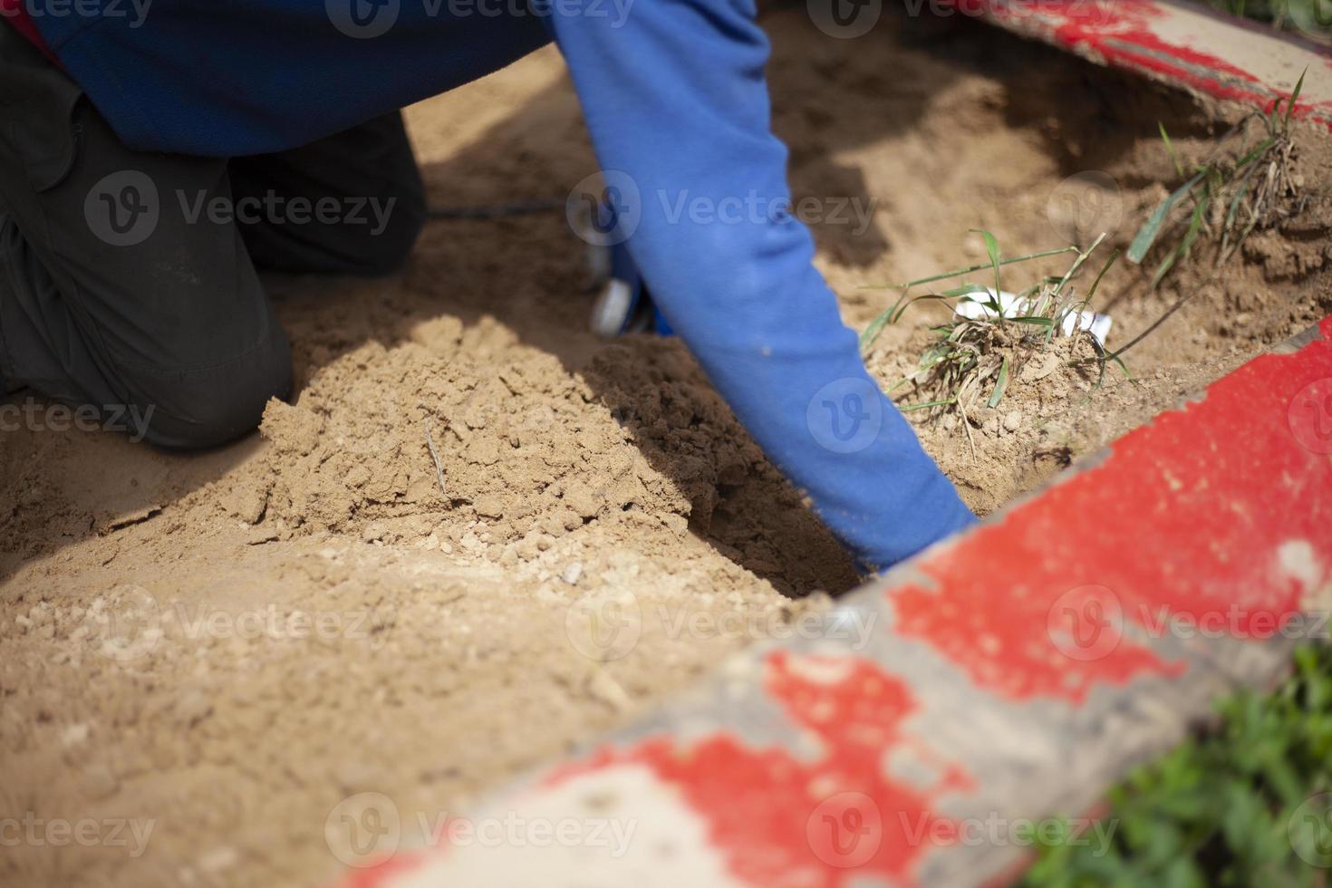 Child in sandbox is playing. Boy on playground. Hands in dog. photo