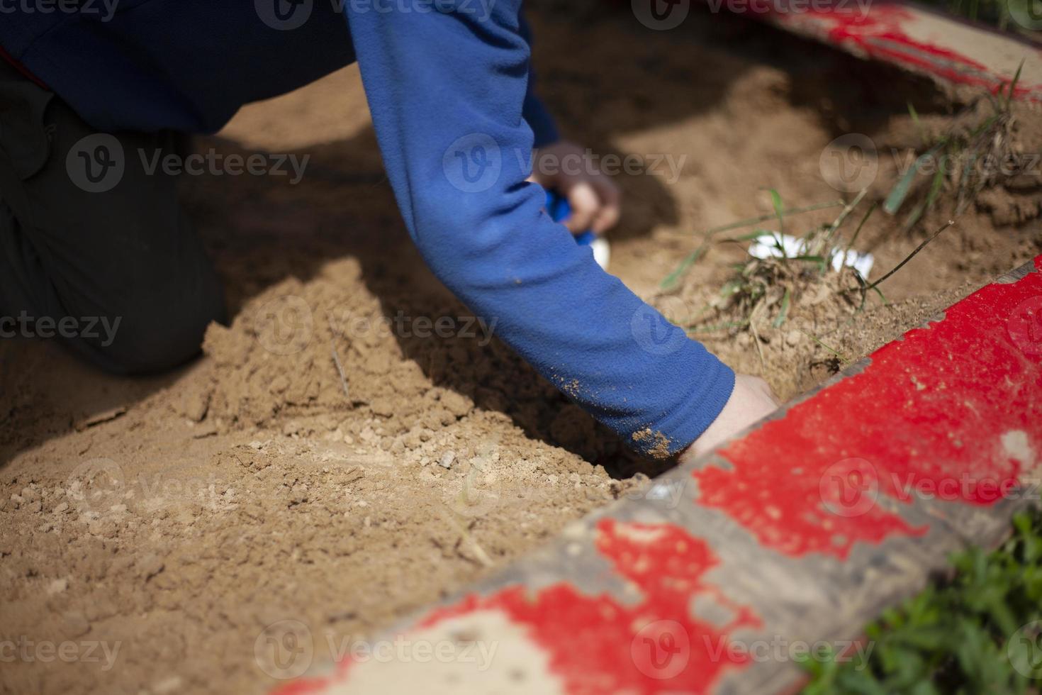 Child in sandbox is playing. Boy on playground. Hands in dog. photo