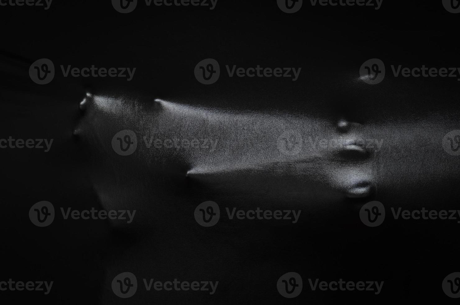 Screaming human face and hand pressing through black fabric with shine and dark side for Halloween background concept. photo