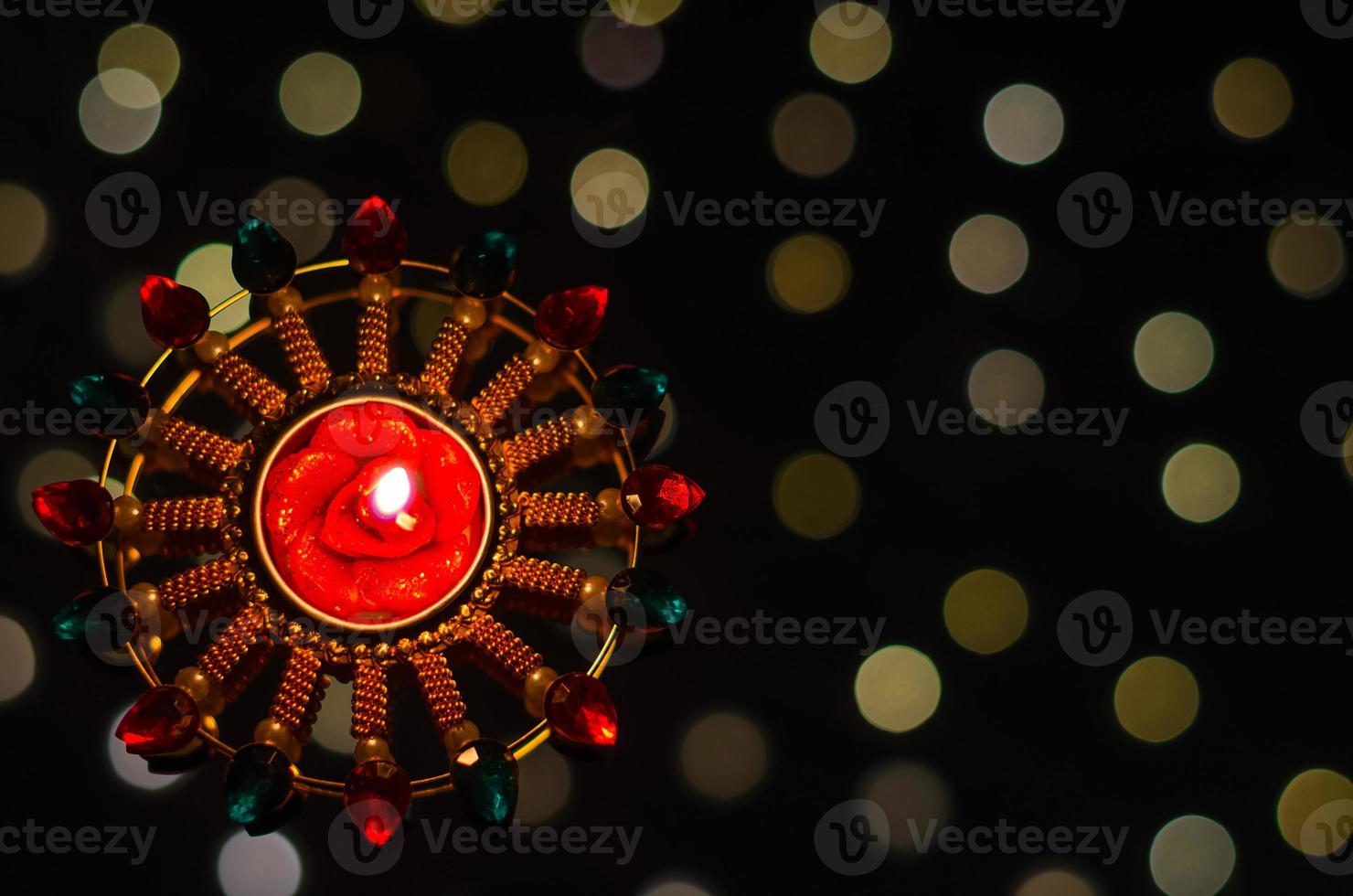 Selective focus on candle of diya lamp lit on dark background with bokeh lights. Diwali festival concept. photo