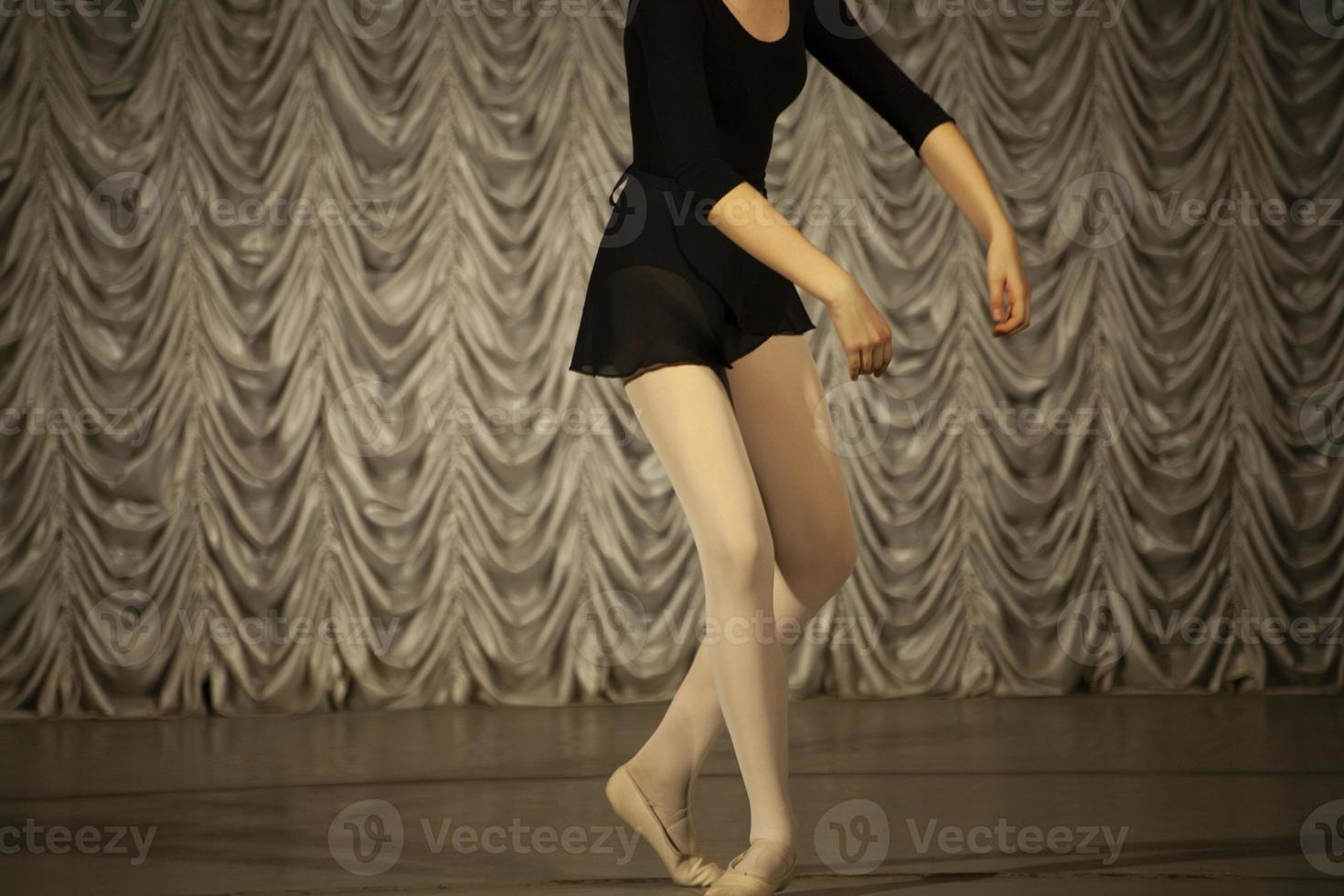 Dancer on stage. Girl in a black dress and Beige tights, front view. photo