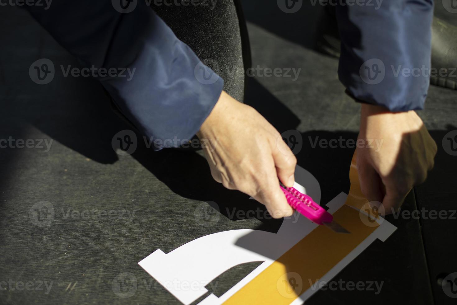 Cutting the adhesive tape. Work with a conceler knife. A person glues a paper figure. photo