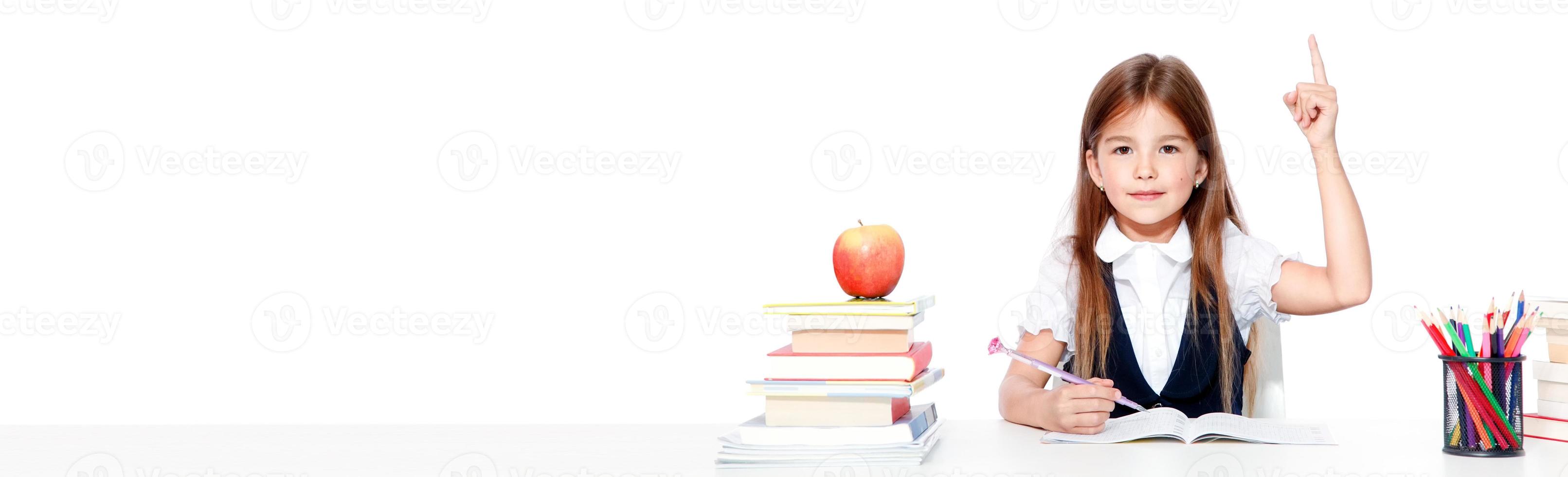 Happy and cute teen schoolgirl raising hand in classroom photo